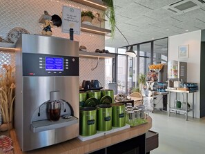 A coffee station with a coffee machine, green canisters, and a sign indicating the café is eco-friendly. - Ibis Styles Le Treport Mers Les Bains (Mers-les-Bains)