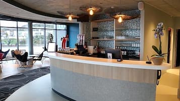 A reception area with a curved counter, a large window, and a potted orchid.