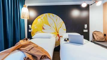 Habitación de hotel con dos camas, una computadora portátil, una mochila, una lámpara de pared y una obra de arte circular grande.