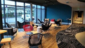 A spacious indoor area with large windows, modern chairs, and a patterned carpet. - Ibis Styles Le Treport Mers Les Bains (Mers-les-Bains)