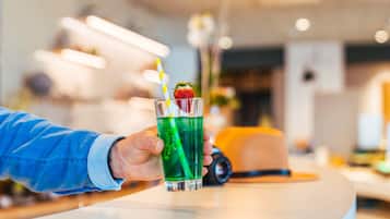 Una mano sosteniendo un vaso con una bebida verde, una pajita y una fresa como adorno.