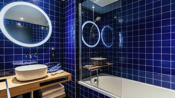 A bathroom with a bathtub, a sink with a mirror, and a shower area.