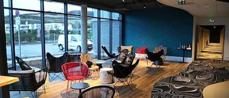 Un espacio interior amplio con ventanas grandes, sillas modernas y una alfombra con estampado.