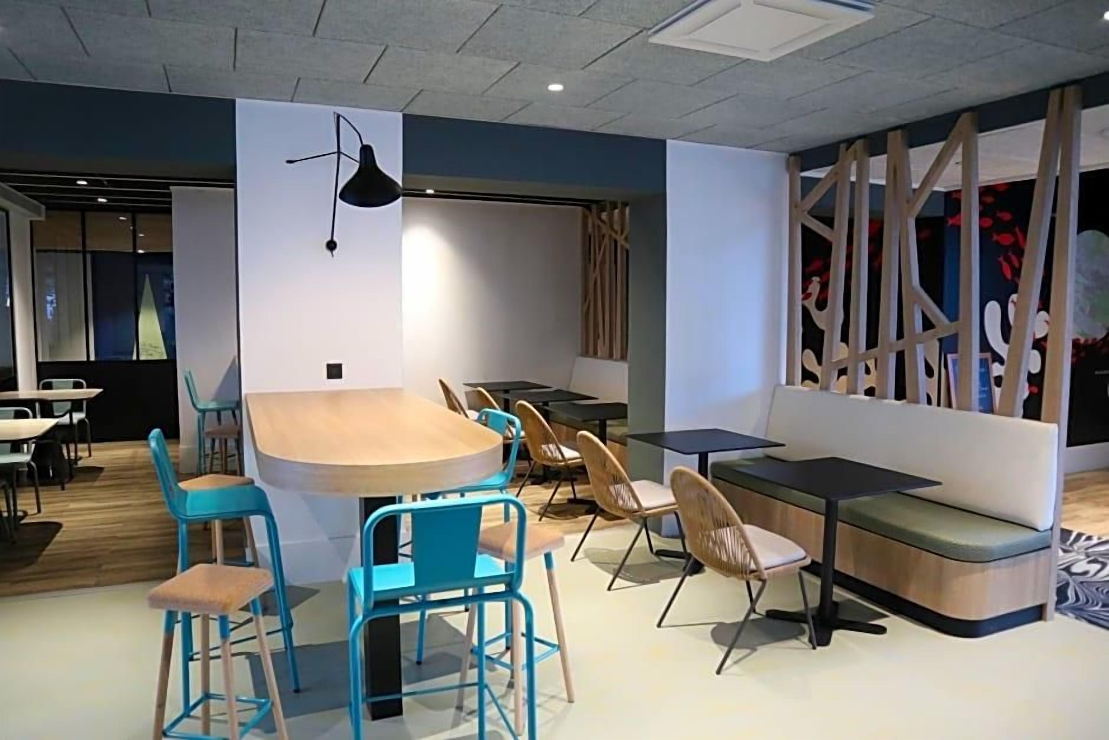 Un intérieur moderne avec une table ronde entourée de chaises, un canapé et un panneau de séparation orné de motifs abstraits.