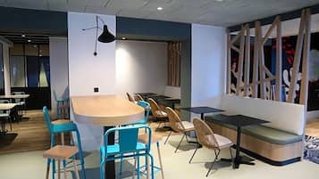 Un intérieur moderne avec une table ronde entourée de chaises, un canapé et un panneau de séparation orné de motifs abstraits.