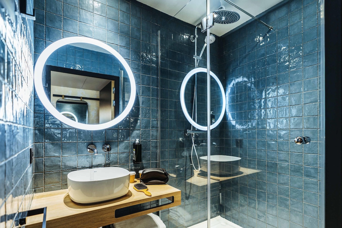 A modern bathroom with a round mirror, a sink, and a shower.