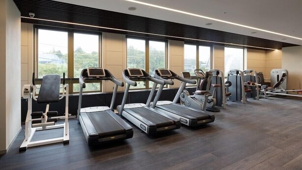 Une salle de sport équipée de tapis de course, de vélos elliptiques et d’appareils de musculation.