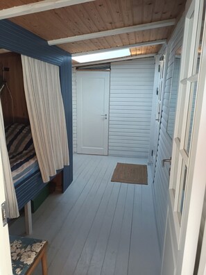 Une pièce avec un lit superposé, une porte, une fenêtre et un petit tapis.