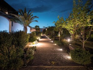 A nighttime pathway leading to a building with a curved facade, surrounded by various plants and trees. - Asty Mykonos Hotel and Spa (Mykonos)