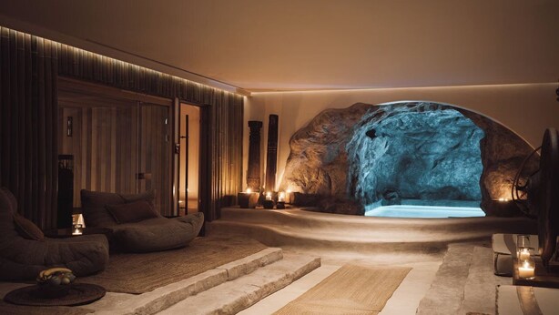 Ein Wellnessbereich mit einer großen Felswand, Sitzgelegenheiten und einem kleinen Pool.