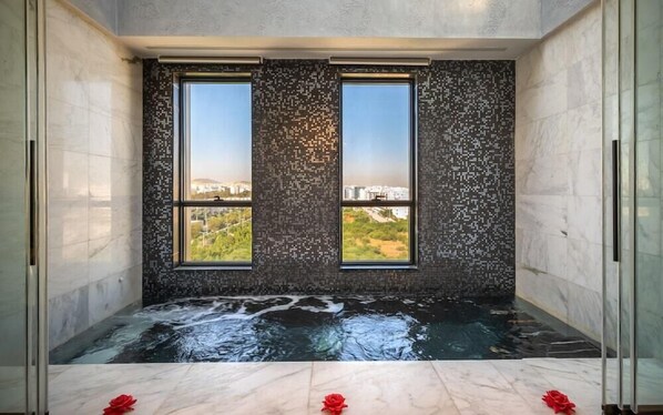A spa room with a large window, a view of a cityscape, and a marble floor. - Royal Asbu (Tunis)