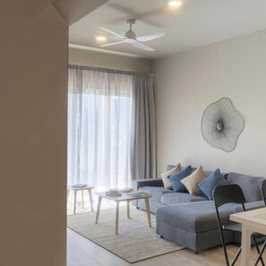 A modern living room with a sofa, a coffee table, a dining table, and a ceiling fan. - Royal Green Wellness Resort (Moka)