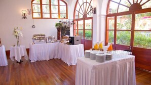 A room with wooden flooring, white tables with tablecloths, and large windows with arched tops. - DM Hoteles Mossone Ica (Ica)