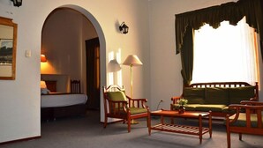 A hotel room with a bed, a green sofa, wooden chairs, a coffee table, and a lamp. - DM Hoteles Mossone Ica (Ica)