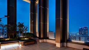 Une terrasse extérieure moderne avec vue sur la ville, caractérisée par un design géométrique avec des lignes illuminées, un banc et une rambarde.