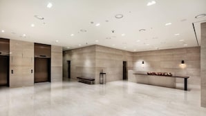 Un hall d’entrée spacieux, doté d’un sol en marbre, d’un éclairage encastré et d’un banc agrémenté d’un arrangement floral.