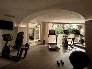 Een sportschool in huis met trainingsapparatuur, een grote spiegel en uitzicht op het buiten.