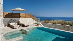 Ein Poolbereich mit freiem Blick auf das Meer, einer Holzterrasse und einer Steinmauer.