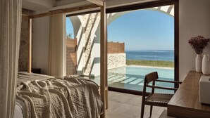 Une chambre avec une grande fenêtre donnant sur une piscine et l’océan.