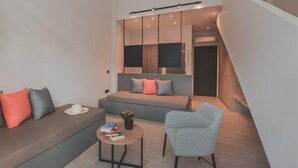 A modern living room with a sofa, armchair, and coffee table. There is a staircase leading to an upper level. - Cavo Suites - Adults Only (Zakynthos)