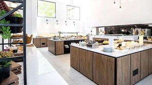 A modern kitchen with wooden cabinets, stainless steel appliances, and a central island with a sink and countertop. - Cavo Suites - Adults Only (Zakynthos)