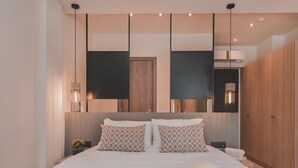 A modern bedroom with a large bed, two bedside tables, a wardrobe, and a hanging light fixture. - Cavo Suites - Adults Only (Zakynthos)