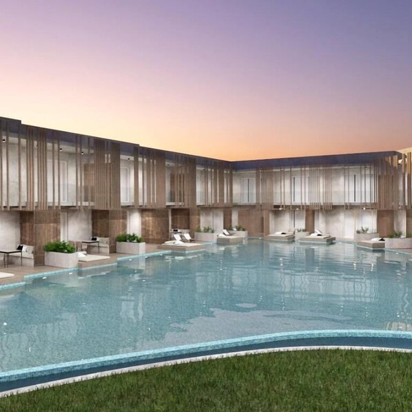 A modern indoor pool area with a clear pool, lounge chairs, and a grassy area in front. - Senseana Sea Side Resort and Aquadventure (Hersonissos)