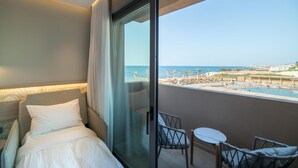 Een hotelkamer met een bed, een glazen deur naar een balkon en uitzicht op een strandresort.