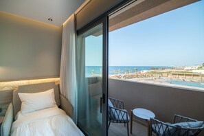 Habitación de hotel con cama, puerta de vidrio que da a un balcón y vista a un resort en la playa.