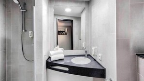A modern bathroom with a shower, a sink, and a mirror. - Ibis Budget Koeln Porz (Cologne)