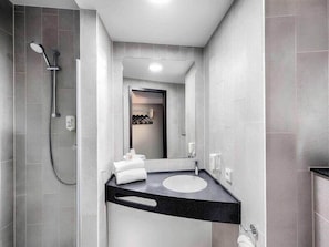 A modern bathroom with a shower, a sink, and a mirror. - Ibis Budget Koeln Porz (Cologne)