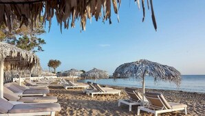 A beach with sun loungers and thatched umbrellas. - Nema Design Hotel and Spa - Adults Only (Hersonissos)