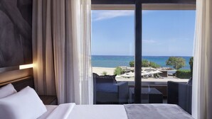 A hotel room with a bed, a view of the beach, and outdoor seating. - Nema Design Hotel and Spa - Adults Only (Hersonissos)
