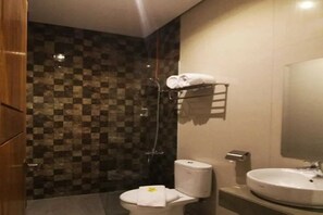 A bathroom with a checkered tile wall, a white sink, a toilet, and a towel rack with towels. - Onesouth Banyuwangi Pulau Merah (Sumberagung)