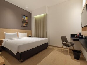 A hotel room with a bed, a chair, a desk, a trash bin, and a painting on the wall. - Hotel 88 Blok M (Jakarta)