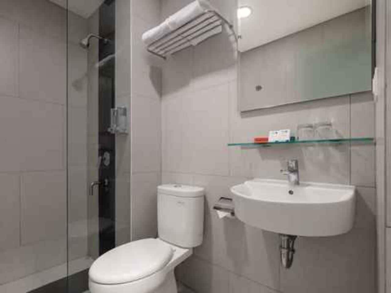 A modern bathroom with a glass shower enclosure, a white toilet, and a wall-mounted sink.
