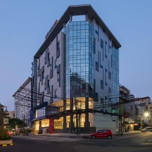 A modern hotel with a glass facade, multiple floors, and a prominent entrance. - Hotel 88 Blok M (Jakarta)
