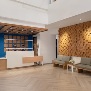 A modern reception area with a wooden wall, a reception desk, and seating. - Hotel 88 Blok M (Jakarta)