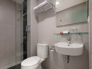 A modern bathroom with a glass shower enclosure, a white toilet, and a white sink with a mirror above. - Hotel 88 Blok M (Jakarta)
