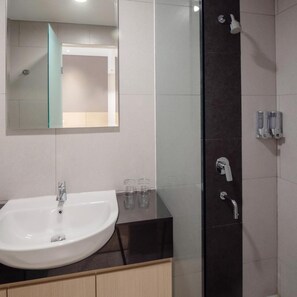A modern bathroom with a white sink, a glass shower enclosure, and a mirror above the sink. - Hotel 88 Blok M (Jakarta)