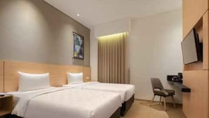 A hotel room with a double bed, a desk, a chair, a television, and a window with curtains. - Hotel 88 Blok M (Jakarta)