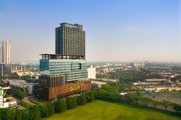 A modern building with a glass facade and a smaller structure on top. - Trembesi Hotel BSD (South Tangerang)