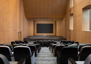 A lecture hall with rows of chairs facing a stage. - Trembesi Hotel BSD (South Tangerang)
