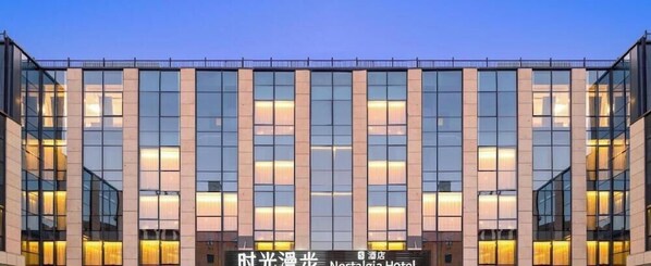 A modern hotel building with a glass facade and illuminated windows. - Nostalgia S Hotel (Beijing)