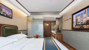 Habitación de hotel con cama, una mesita de noche con lámpara, baño con espejo y vista panorámica de la ciudad.