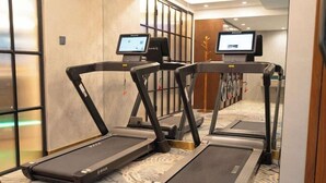 Un pasillo de hotel con cintas de correr, un quiosco digital y una alfombra estampada.