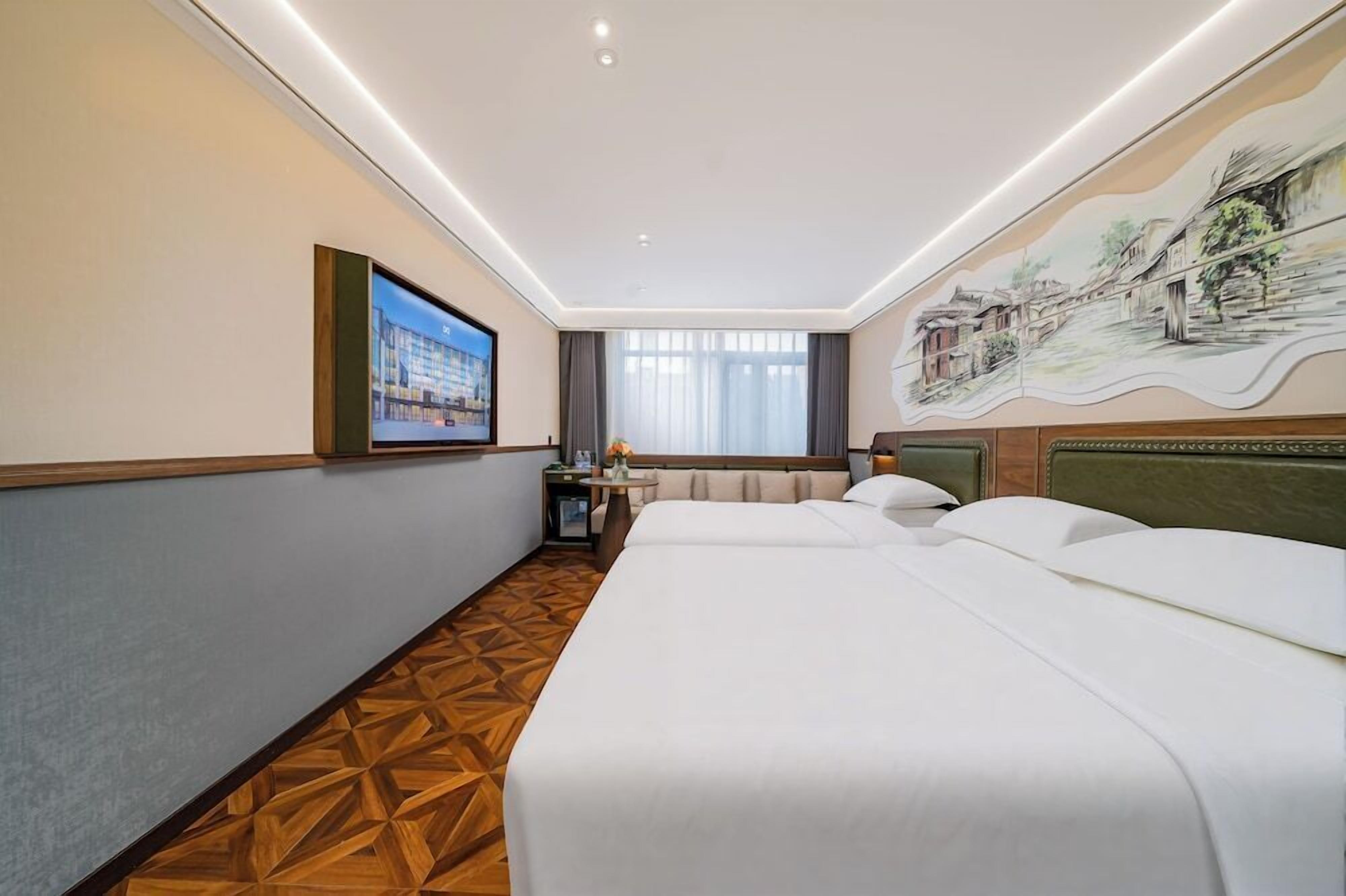 Een hotelkamer met een groot bed, een bureau, een stoel, een televisie en een muurschildering.