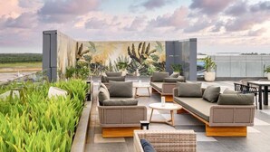 A rooftop lounge with outdoor seating, a mural, and a view of the landscape. - Aston Sorong Hotel and Conference Center (Sorong)