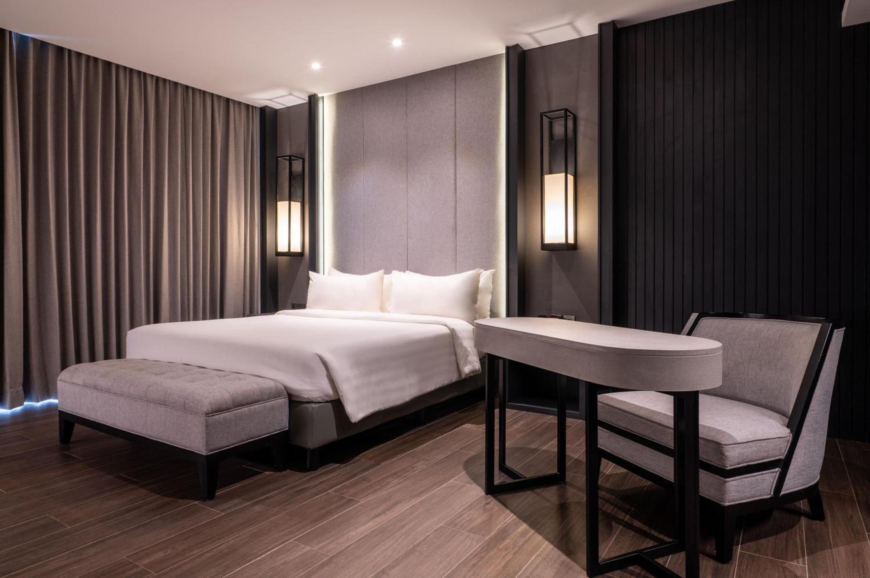Habitación de hotel moderna con una cama grande, una mesita y una silla.