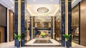A modern lobby with marble columns, a central chandelier, and a reception area. - Aston Sorong Hotel and Conference Center (Sorong)
